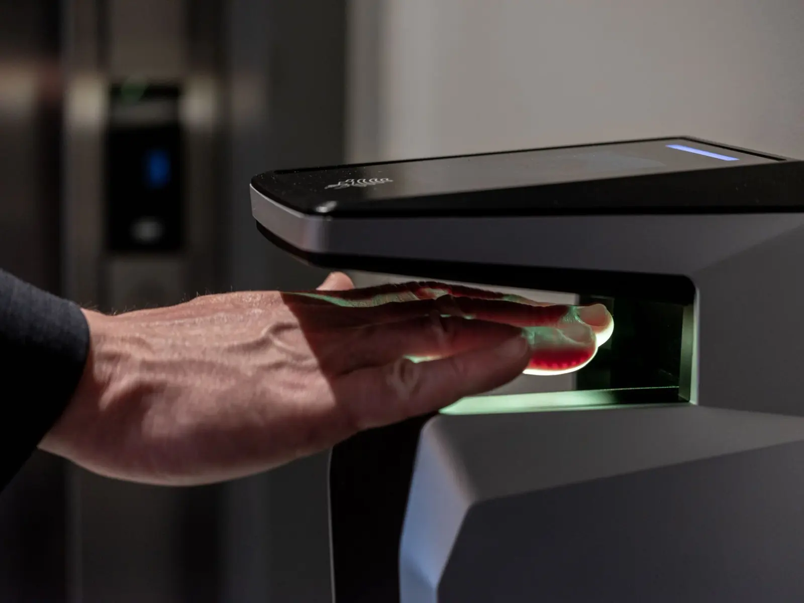 A hand held over a biometric palm reader at a data hall entrance.